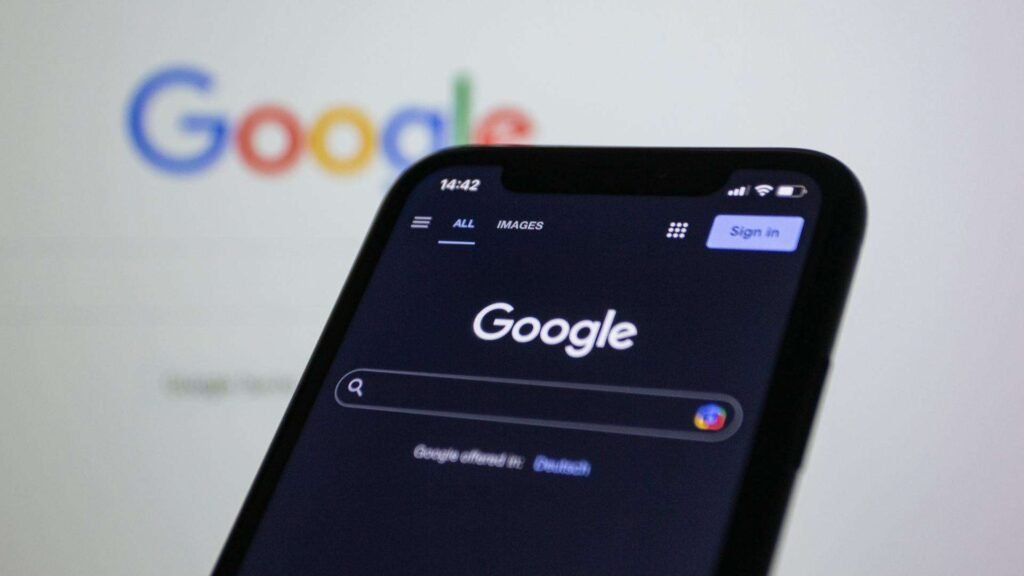 Téléphone intelligent montrant le site web Google en avant-plan et, en arrière-plan, le site web Google sur un écran d'ordinateur.